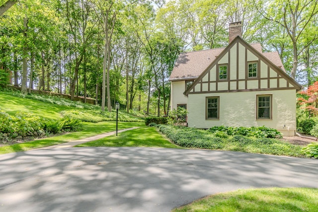 2430 Geddes Ave, Ann Arbor, MI 48104 - view of side of property with stucco siding, a chimney, a shingled roof, and a lawn