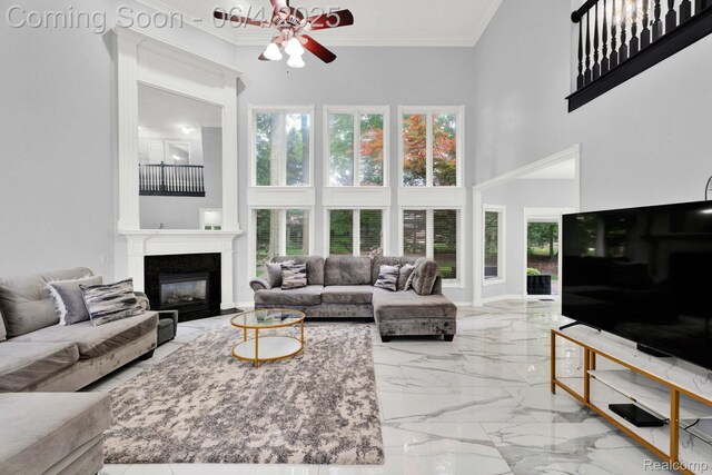 50565 Otter Creek Dr, Shelby Twp, MI 48317 - living area with a towering ceiling, a ceiling fan, marble tiled flooring, a glass covered fireplace, and ornamental molding