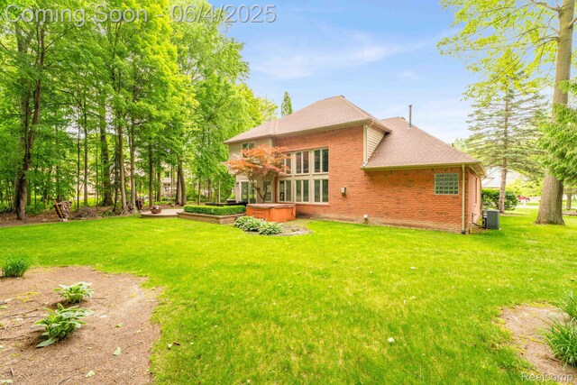 50565 Otter Creek Dr, Shelby Twp, MI 48317 - back of property featuring central AC, brick siding, a yard, and roof with shingles