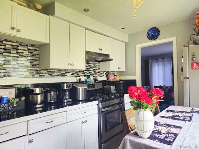 22189 Albion Ave, Farmington Hills, MI 48336 - kitchen featuring under cabinet range hood, stainless steel gas range oven, freestanding refrigerator, white cabinetry, and decorative backsplash