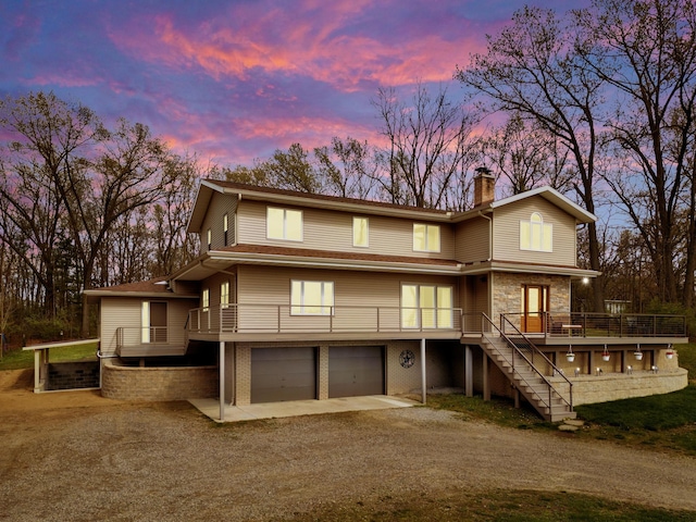 175 Templar Ave, Pinckney, MI 48169 - back of property at dusk with dirt driveway, a garage, stairway, a chimney, and a wooden deck