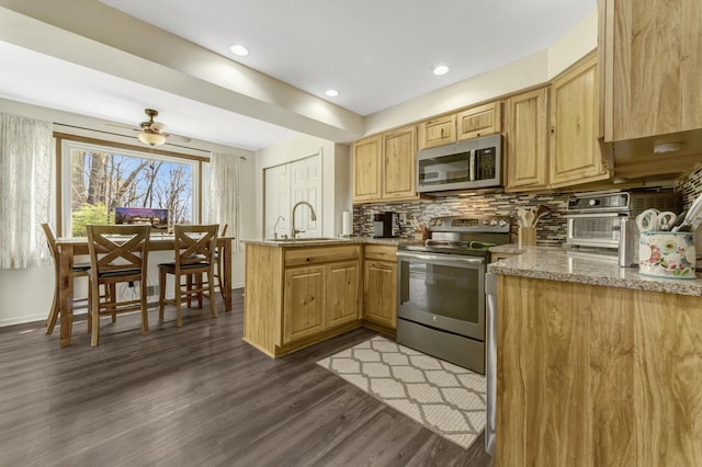 175 Templar Ave, Pinckney, MI 48169 - kitchen featuring appliances with stainless steel finishes, a peninsula, dark wood-style floors, backsplash, and a sink