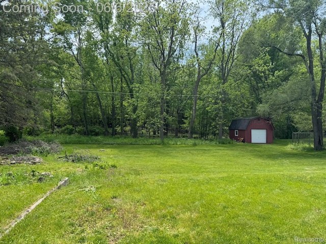 4327 Lancashire, Milford, MI 48380 - view of grassy yard with a detached garage, an outdoor structure, and a forest view