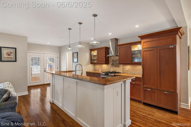 797 Washington Rd, Grosse Pointe, MI 48230 - kitchen featuring wall chimney range hood, stainless steel range with gas stovetop, brown cabinets, paneled built in refrigerator, and dark wood-style floors