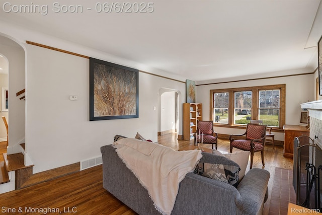 797 Washington Rd, Grosse Pointe, MI 48230 - living room with arched walkways, dark wood-style floors, a brick fireplace, stairs, and baseboards
