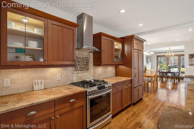 797 Washington Rd, Grosse Pointe, MI 48230 - kitchen with stainless steel gas range oven, wall chimney range hood, brown cabinets, a chandelier, and recessed lighting