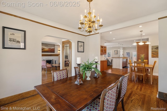 797 Washington Rd, Grosse Pointe, MI 48230 - dining area featuring wood finished floors, arched walkways, a warm lit fireplace, recessed lighting, and a chandelier