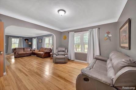 4131 Wellman Line Rd, Brown City, MI 48416 - living room featuring arched walkways, light wood finished floors, and crown molding
