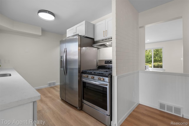 32532 Steinhauer St, Westland, MI 48186 - kitchen with stainless steel appliances, under cabinet range hood, white cabinets, light wood-style flooring, and wainscoting