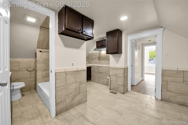 3851 Fredro St, Hamtramck, MI 48212 - bathroom with tile walls, toilet, a tub, a wainscoted wall, and vaulted ceiling
