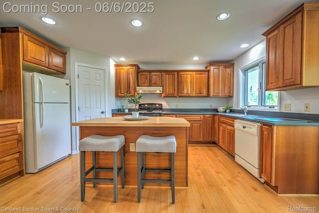 11265 N Shore Dr, Whitmore Lake, MI 48189 - kitchen with white appliances, brown cabinetry, a kitchen island, a breakfast bar, and under cabinet range hood