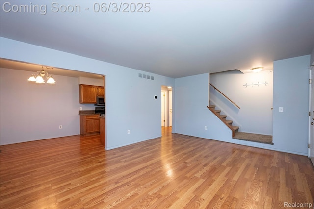 35485 Stillmeadow Ln, Clinton Township, MI 48035 - unfurnished living room featuring a chandelier, light wood-style flooring, and stairs