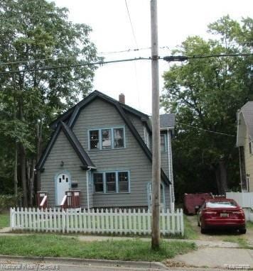 1035 Maple Ave, Jackson, MI 49203 - colonial inspired home featuring a fenced front yard, a gambrel roof, and a chimney