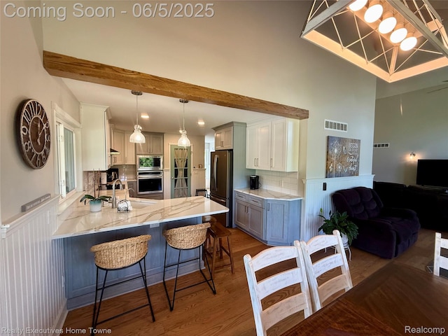 13999 French Ln, Davisburg, MI 48350 - kitchen featuring stainless steel appliances, a peninsula, wood finished floors, a sink, and light stone countertops