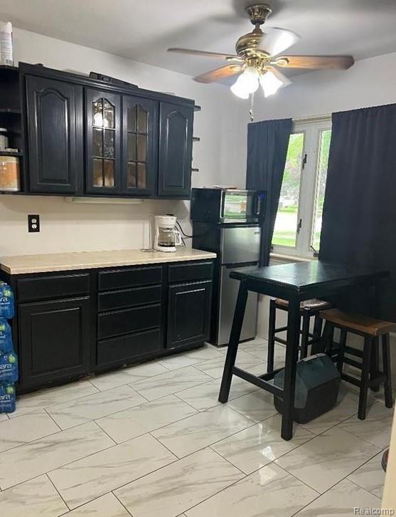 41541 Mcbride Ave, Van Buren, MI 48111 - kitchen featuring light marble finish flooring, freestanding refrigerator, a ceiling fan, light countertops, and dark cabinets