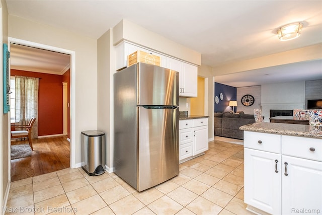 2655 Aspen Ln, Bloomfield Hills, MI 48302 - kitchen with freestanding refrigerator, light tile patterned floors, open floor plan, white cabinetry, and a brick fireplace