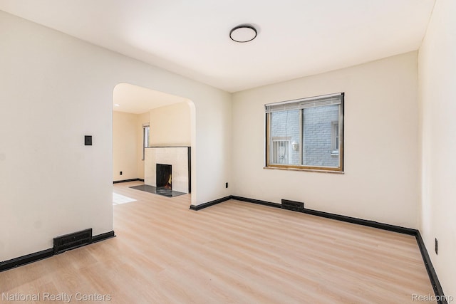 18691 Greenlawn St, Detroit, MI 48221 - spare room with wood finished floors, a tiled fireplace, arched walkways, and baseboards