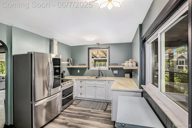 11393 Outer Dr, Pinckney, MI 48169 - kitchen with stainless steel appliances, open shelves, a sink, arched walkways, and wood finished floors