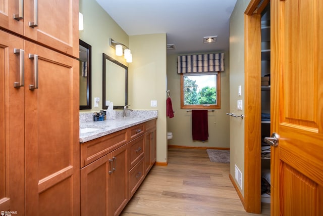 353 Golfside Dr, Lapeer, MI 48446 - bathroom featuring toilet, double vanity, wood finished floors, and baseboards