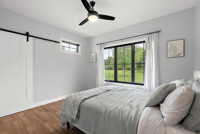 8011 Date Rd, Stevensville, MI 49127 - bedroom with a barn door, wood finished floors, baseboards, and a ceiling fan