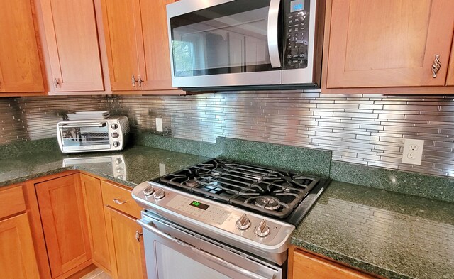 908 W Oak St, Bitely, MI 49309 - kitchen featuring appliances with stainless steel finishes, decorative backsplash, and dark stone countertops