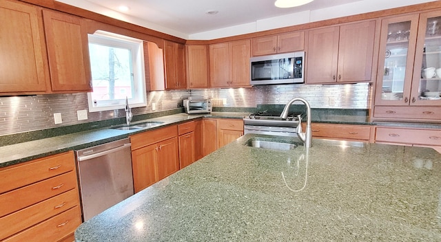 908 W Oak St, Bitely, MI 49309 - kitchen with appliances with stainless steel finishes, a sink, dark stone countertops, and backsplash