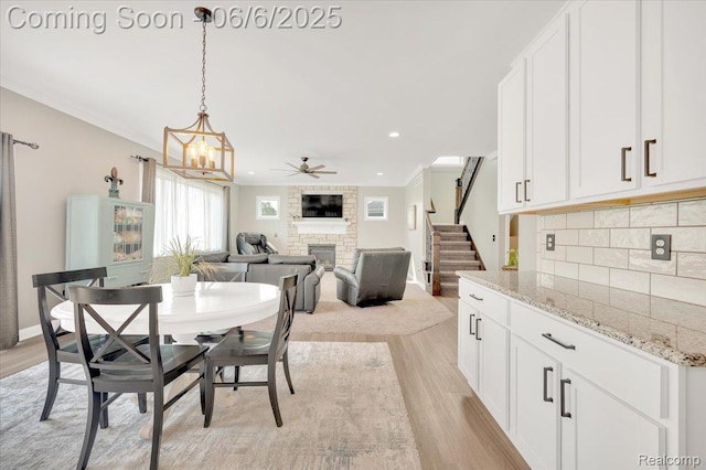 343 Hidden Riv E, Holly, MI 48442 - dining space with a fireplace, stairs, light wood-style flooring, a ceiling fan, and recessed lighting