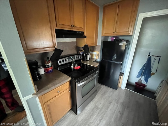 8810 Farmbrook St, Grosse Pointe, MI 48224 - kitchen with stainless steel electric range, freestanding refrigerator, under cabinet range hood, light wood-type flooring, and light countertops