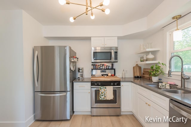 1731 Edgewood Ave SE, Grand Rapids, MI 49506 - kitchen with stainless steel appliances, a sink, dark countertops, white cabinets, and a chandelier