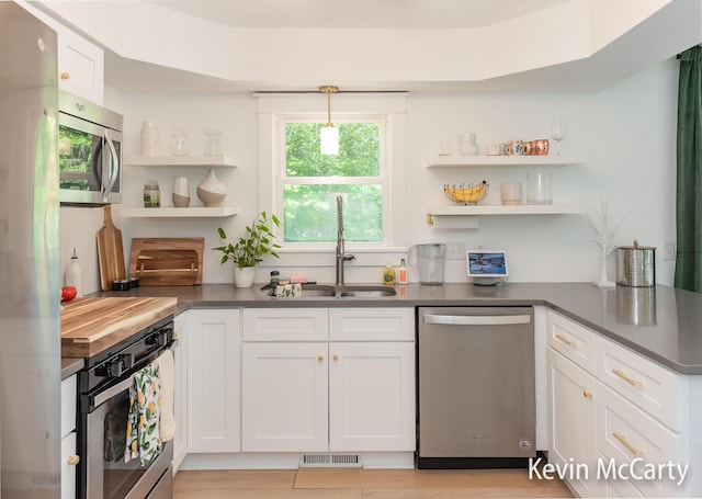 1731 Edgewood Ave SE, Grand Rapids, MI 49506 - kitchen with stainless steel appliances, open shelves, a sink, dark countertops, and white cabinets