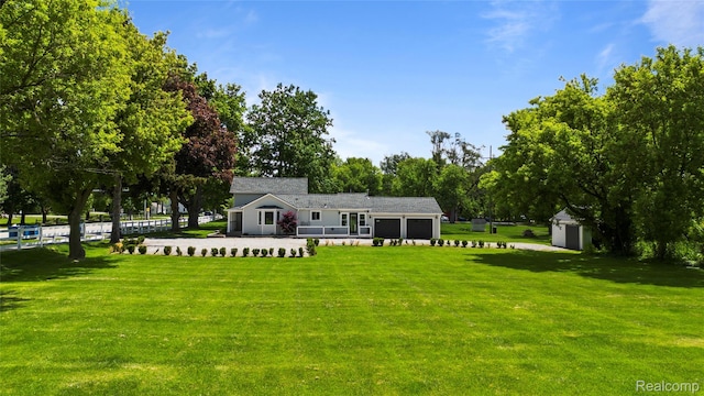 5164 Plymouth Rd, Ann Arbor, MI 48105 - view of front of house with an attached garage, a front yard, a storage unit, and view of wooded area