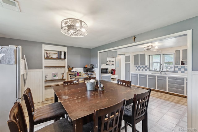 4828 Rathbun Rd, Birch Run, MI 48415 - dining space featuring a wainscoted wall, a chandelier, and light floors