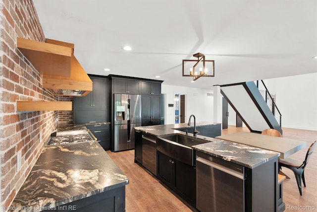 5080 Tootmoor Rd, Bloomfield Hills, MI 48302 - kitchen with stainless steel appliances, a sink, light wood-type flooring, a center island with sink, and a chandelier