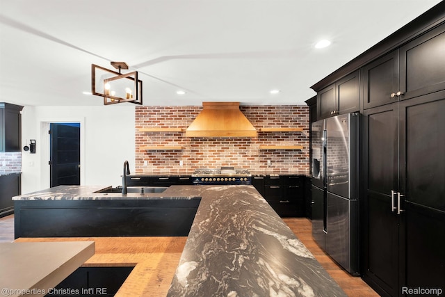 5080 Tootmoor Rd, Bloomfield Hills, MI 48302 - kitchen with stainless steel appliances, a sink, custom exhaust hood, dark stone countertops, and light wood-style flooring