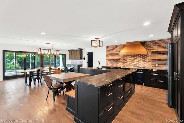 5080 Tootmoor Rd, Bloomfield Hills, MI 48302 - kitchen featuring custom exhaust hood, dark cabinets, gas range oven, light wood-type flooring, and a spacious island