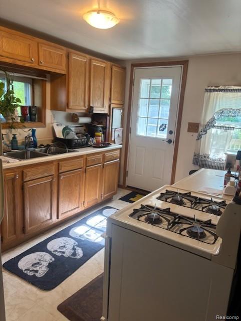 3231 Parker St, Port Huron, MI 48060 - kitchen featuring white gas range, light countertops, a sink, and brown cabinets