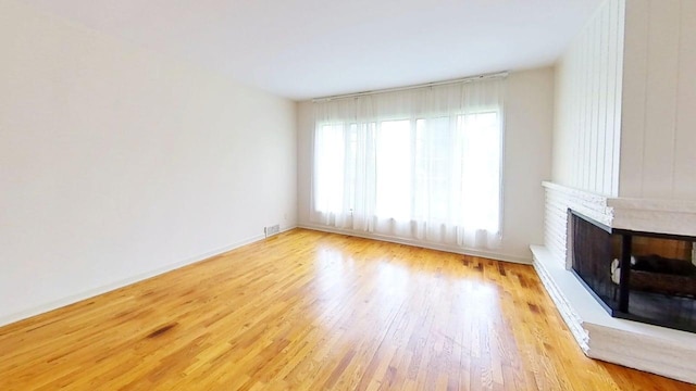 1635 Woodside Dr, East Lansing, MI 48823 - unfurnished living room featuring wood finished floors, a brick fireplace, and baseboards