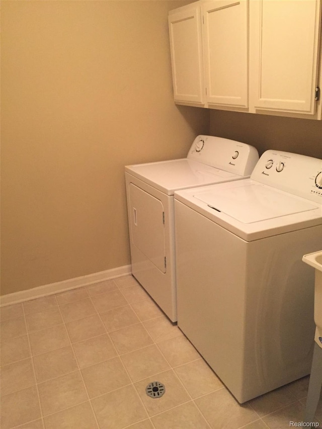 49225 W Woods Dr Unit 20, Utica, MI 48317 - laundry area with washer and clothes dryer, cabinet space, baseboards, and light tile patterned floors