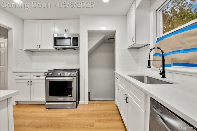9248 Manor St, Detroit, MI 48204 - kitchen with appliances with stainless steel finishes, a sink, tasteful backsplash, white cabinetry, and light countertops
