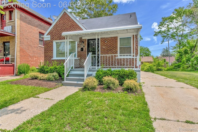 9248 Manor St, Detroit, MI 48204 - view of front of house with brick siding, a front yard, and covered porch