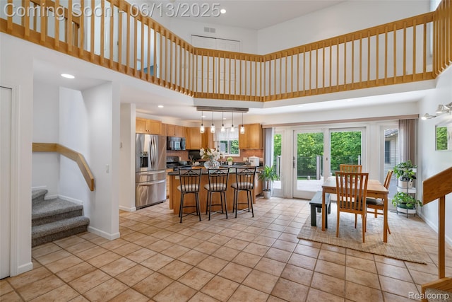 4230 Mill Lake Rd, Lake Orion, MI 48360 - kitchen featuring stainless steel refrigerator with ice dispenser, a towering ceiling, a kitchen island, a kitchen breakfast bar, and decorative light fixtures