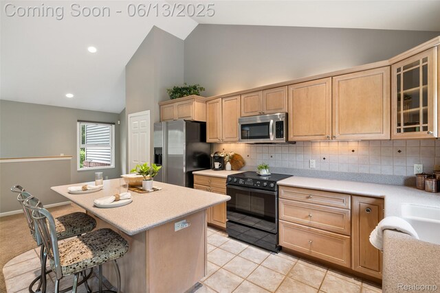 4230 Mill Lake Rd, Lake Orion, MI 48360 - kitchen with stainless steel appliances, light brown cabinetry, a center island, light countertops, and high vaulted ceiling