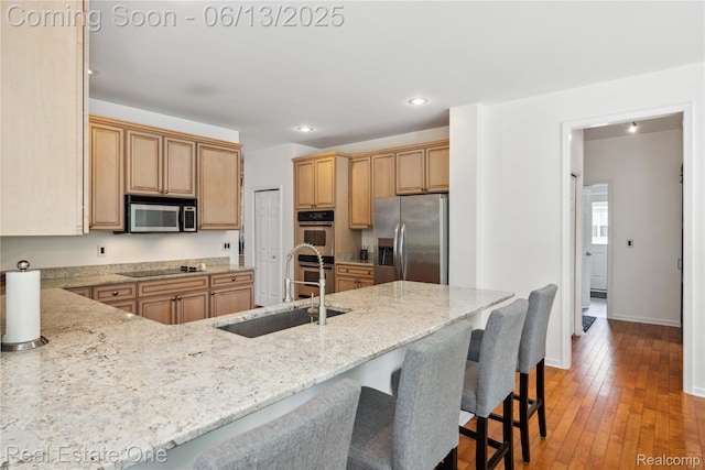 3788 High Grove Way, Lake Orion, MI 48360 - kitchen featuring stainless steel appliances, a sink, light stone counters, a breakfast bar area, and baseboards