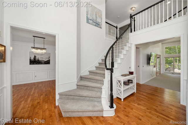3788 High Grove Way, Lake Orion, MI 48360 - staircase with wood finished floors, a chandelier, a towering ceiling, and a decorative wall