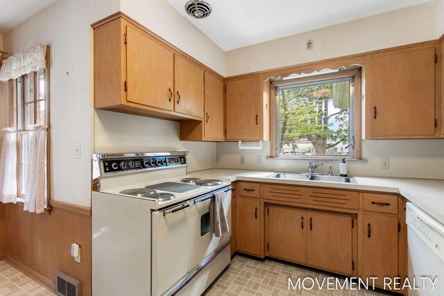 1001 Cricklewood St SW, Wyoming, MI 49509 - kitchen with white appliances, a sink, light countertops, brick patterned flooring, and a wainscoted wall