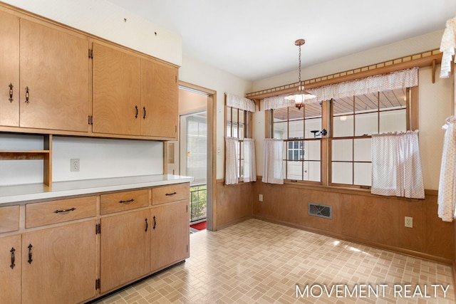 1001 Cricklewood St SW, Wyoming, MI 49509 - kitchen with brick patterned flooring, light countertops, pendant lighting, baseboards, and wood walls