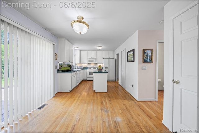 2105 Rob Rdg, Commerce Twp, MI 48390 - kitchen with white appliances, white cabinetry, light wood-type flooring, dark countertops, and a kitchen island