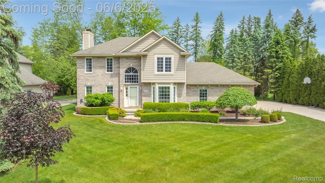 2105 Rob Rdg, Commerce Twp, MI 48390 - view of front of property with a chimney, brick siding, a front yard, driveway, and roof with shingles
