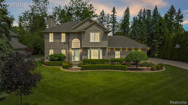 2105 Rob Rdg, Commerce Twp, MI 48390 - view of front of home with a chimney, a lawn, driveway, and brick siding