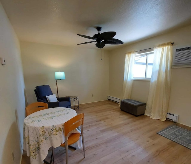 202 E Water Ave, Oscoda, MI 48750 - sitting room featuring a baseboard radiator, an AC wall unit, light wood-style flooring, and ceiling fan